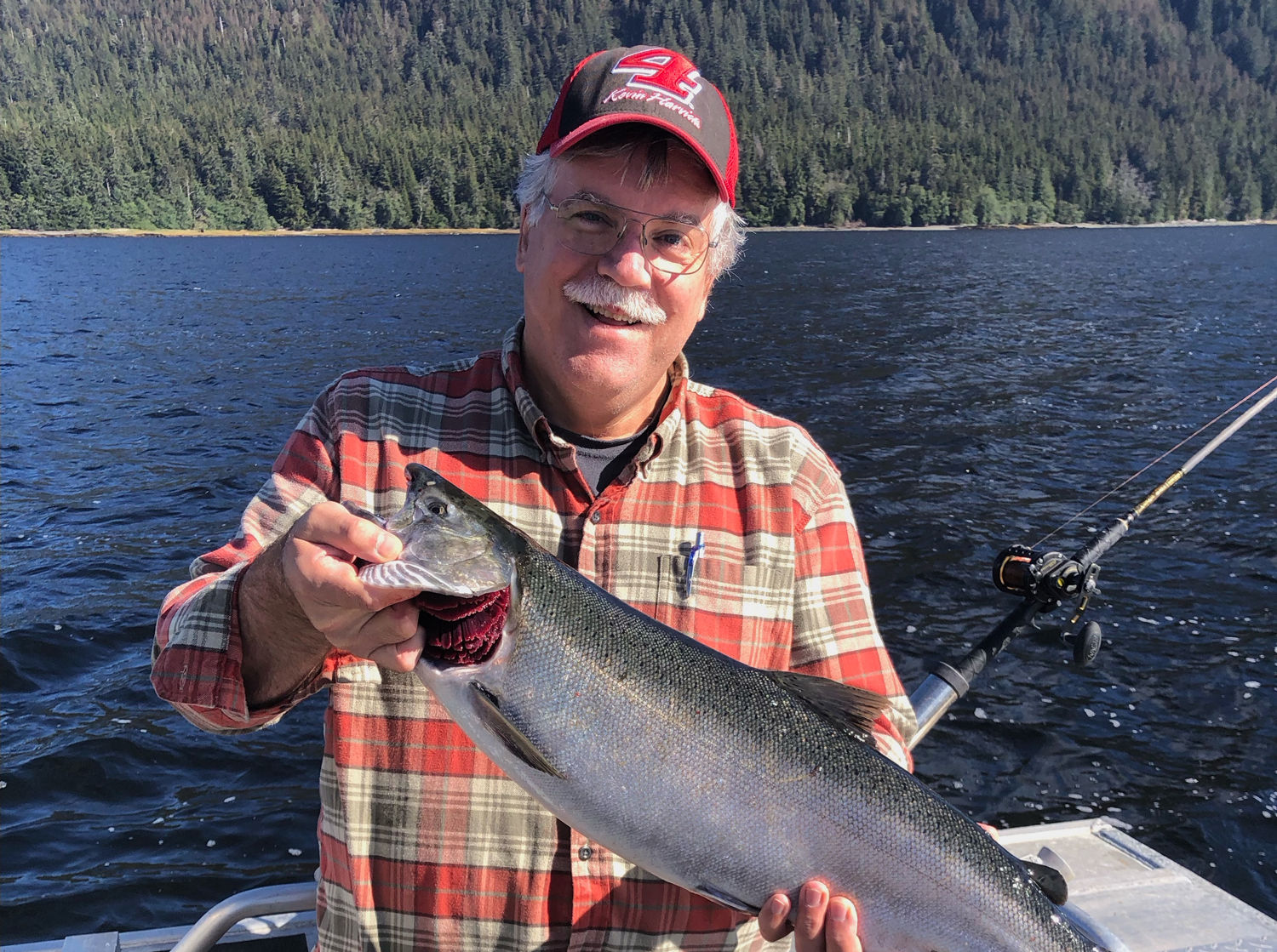 Jeff Ryan holding a Salmon while standing on the back of a fishing boat.